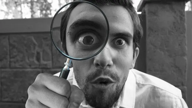 Man looking through magnifying glass